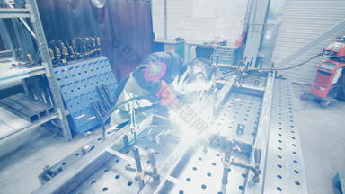 工人保护西装面具进行金属焊接工厂焊机